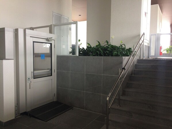 Escada com corrimão de metal que leva a uma porta com janela.