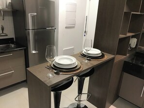 A modern kitchen with a built-in refrigerator, a dining area with two stools, and a wall-mounted light fixture. - Studio London near Paulista w/ Parking LA804 (São Paulo)
