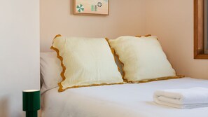 Ein Bett mit zwei Kissen, einer Nachttischlampe und einem gefalteten Handtuch.