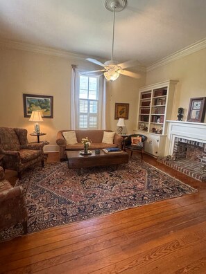 A living room with a sofa, armchairs, a coffee table, a fireplace, and a bookshelf. - Historic Cottage near MSU, Old Waverly & Mossy Oak (West Point)