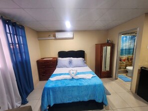A hotel room with a bed, a wardrobe, a mirror, and a bathroom. - Affordable, self contained studio, 8-10 mins from the Piarco Intl Airport (Arima)