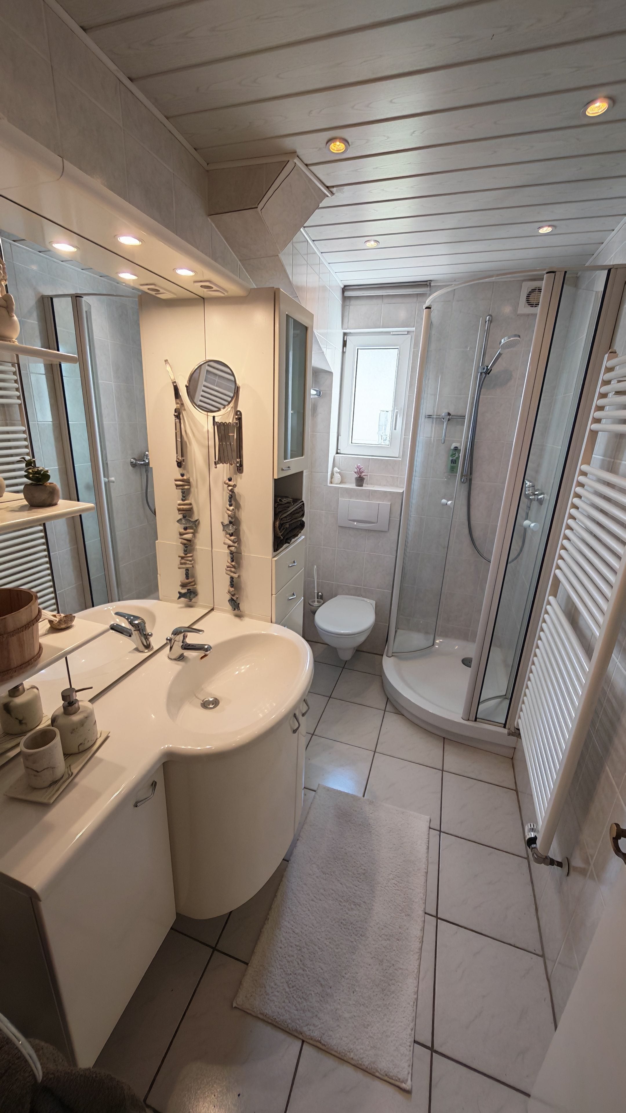 Ein modernes Badezimmer mit einem großen Waschbecken, einem Spiegel und einer Dusche.