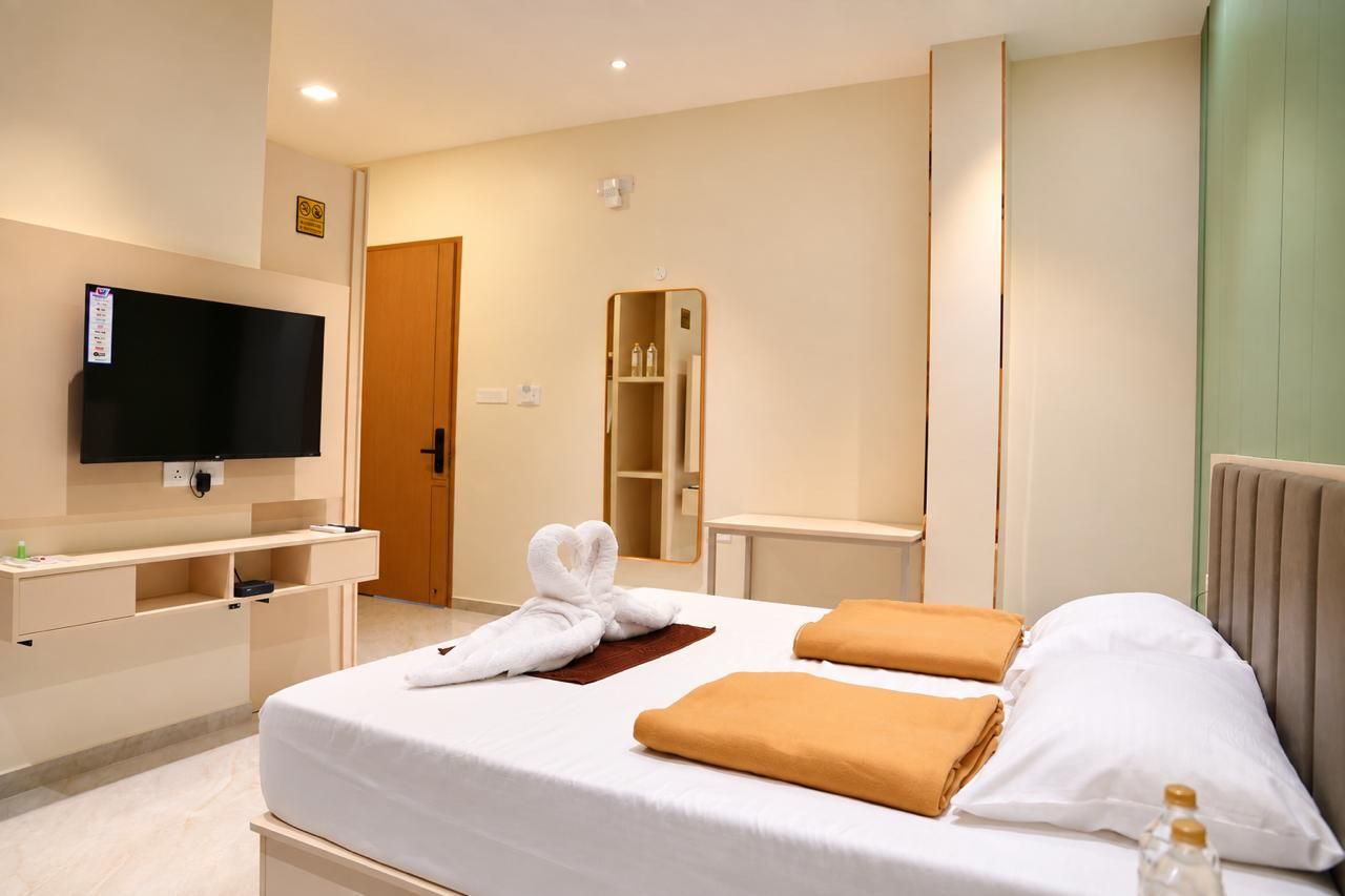 Habitació d'hotel amb un llit, televisió, armari i mirall.