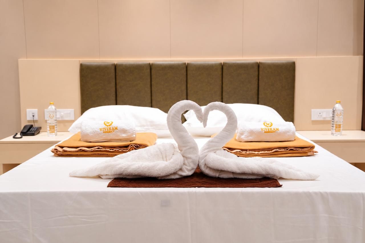 Quarto de hotel com uma cama, duas toalhas moldadas como cisnes e uma toalha Viveram sobre a cama.