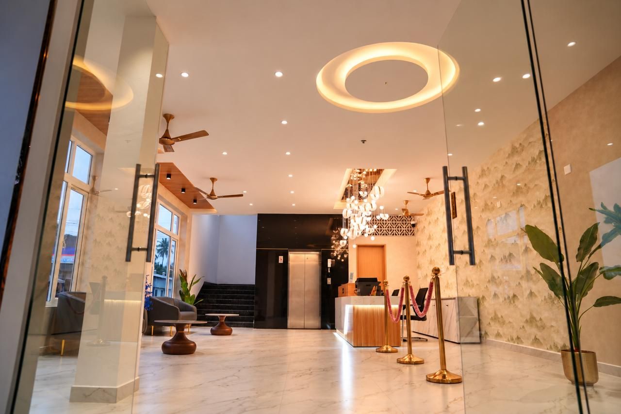 A hotel lobby with a reception desk, seating area, and a staircase leading to an upper floor.