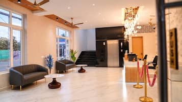 Eine Hotelhalle mit Empfangstresen, Sitzgelegenheiten und einer Treppe.