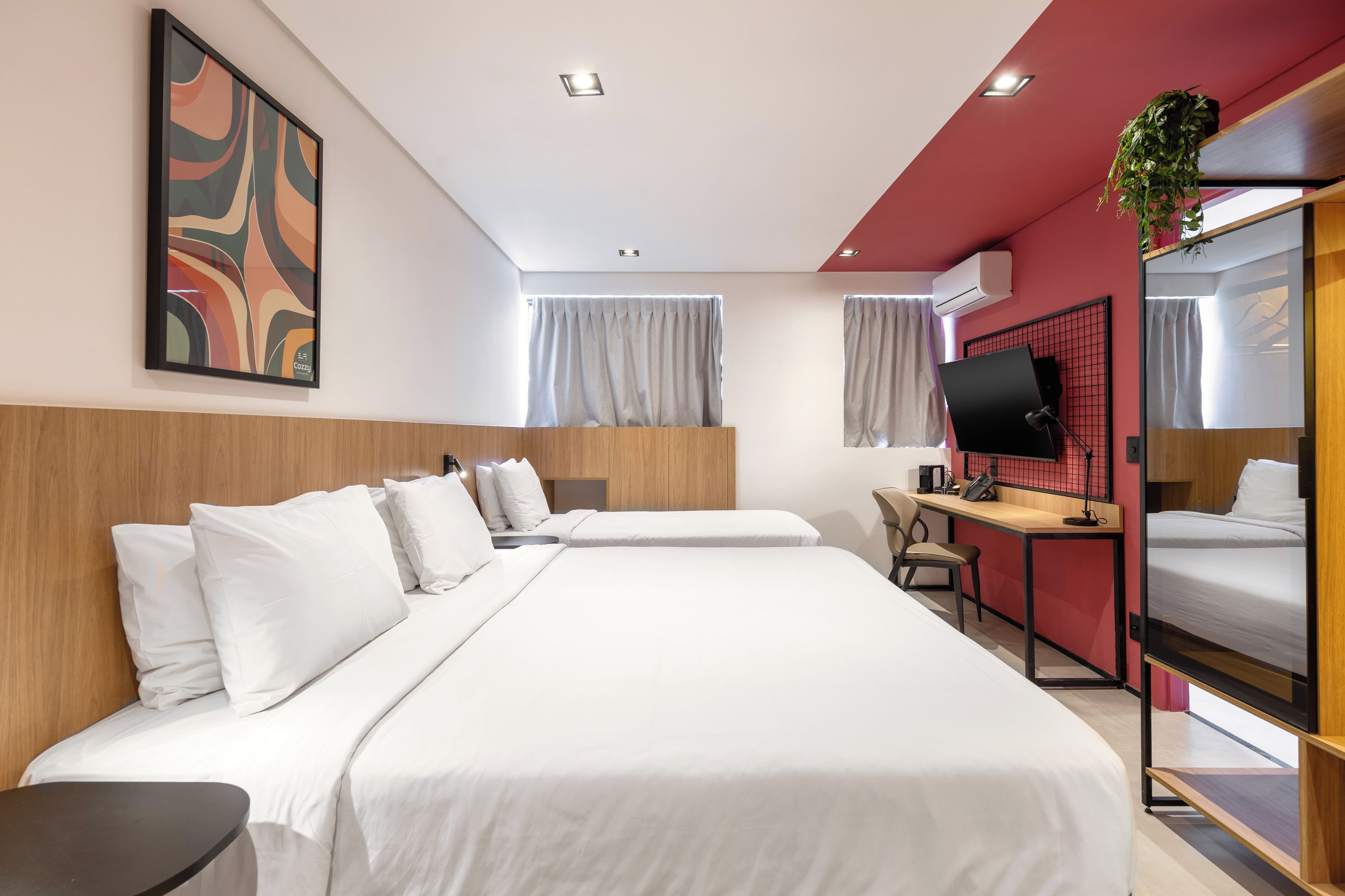 Ein Hotelzimmer mit einem großen Bett, einem Schreibtisch, einem Sessel, einem Fernseher und einer Pflanze.