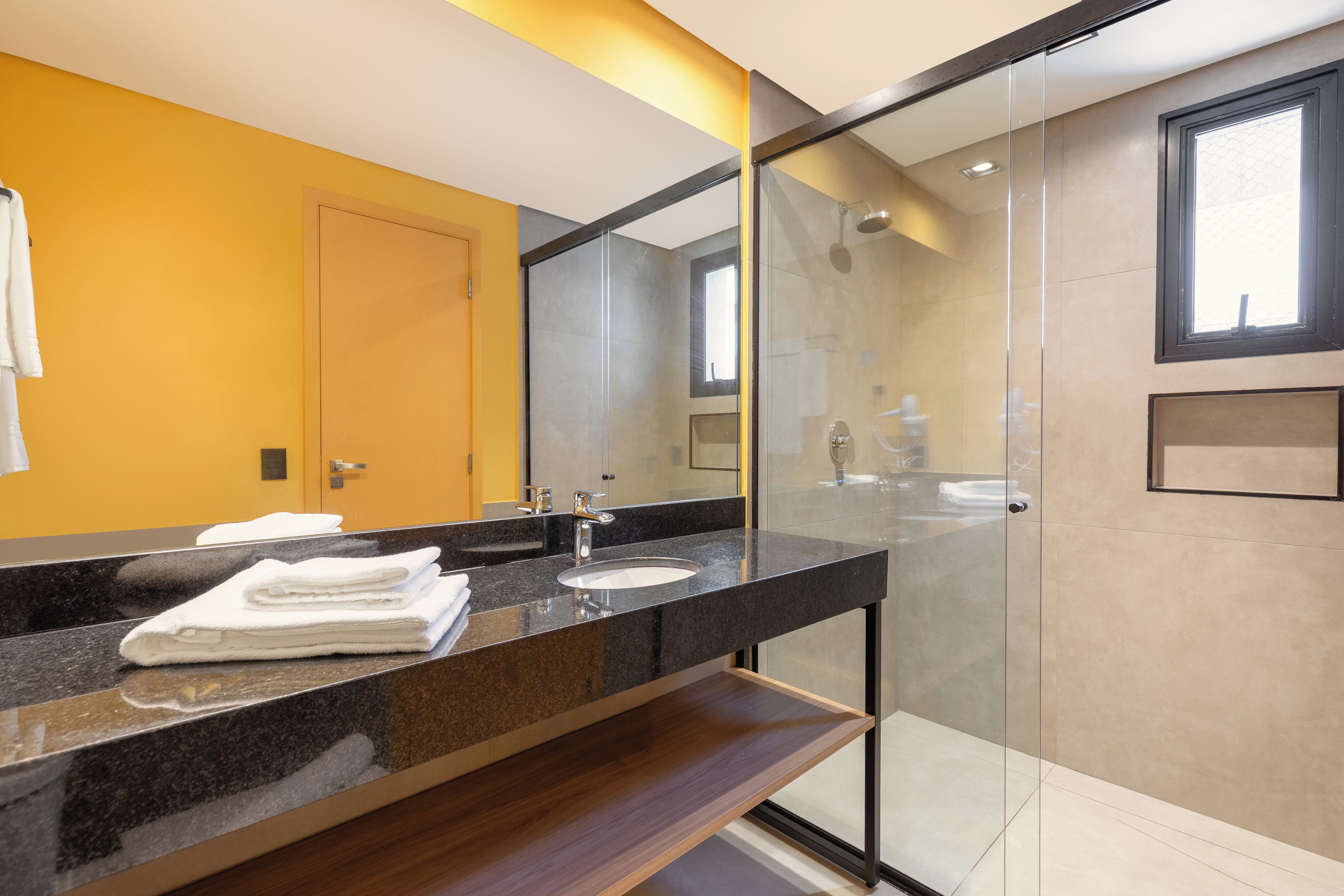 A modern bathroom with a glass shower enclosure, a vanity with a sink, and a mirror.