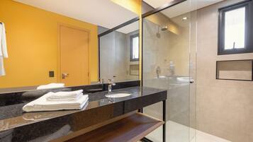 Un baño moderno con cabina de ducha de vidrio, tocador con lavabo y espejo.