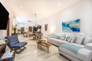 Una sala de estar moderna con sofá, sillón, mesa de centro y un comedor con sillas y una mesa.