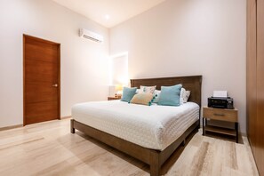 Ein Schlafzimmer mit einem hölzernen Bett, einem Nachttisch, einer Lampe und einer Klimaanlage an der Wand.