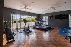 Ein Fitnessstudio mit Trainingsgeräten, großen Fenstern und einem motivierenden Zitat an der Wand.