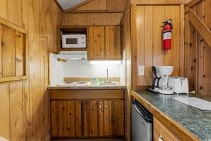 Een compacte keuken met houten kastjes, een magnetron, een koffiezetapparaat en een vaatwasser.