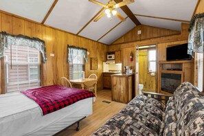 A cozy cabin with a bed, a sofa, a kitchenette, and a fireplace. - One Room Parkview Cabin - Sleeps 2 to 4 guests. (Gore)