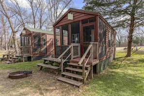 Two wooden cabins with large windows and a porch, surrounded by trees. - One Room Parkview Cabin - Sleeps 2 to 4 guests. (Gore)