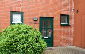 A brick building with a green door, two windows, and a small bush in front. - Beautiful apartment in Ribnitz-Damgarten with WiFi (Ribnitz-Damgarten)