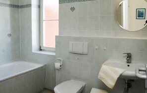 Ein Badezimmer mit Badewanne, Toilette, Waschbecken und einem Fenster.