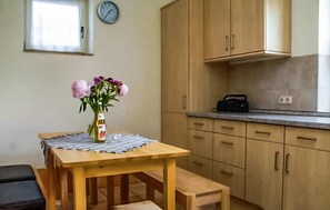 A kitchen with wooden cabinets, a clock on the wall, and a table with a bottle of olive oil. - Beautiful apartment in Ribnitz-Damgarten with WiFi (Ribnitz-Damgarten)