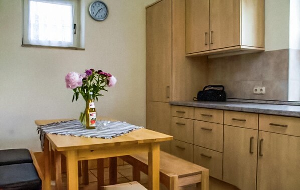 Eine Küche mit Holzausstattung, einer Uhr an der Wand und einem Tisch mit einer Flasche Olivenöl.