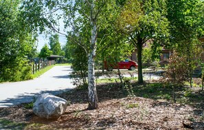 A paved pathway in a park with trees and a red car parked nearby. - 3 bedroom beautiful home in Ribnitz-Damgarten (Ribnitz-Damgarten)