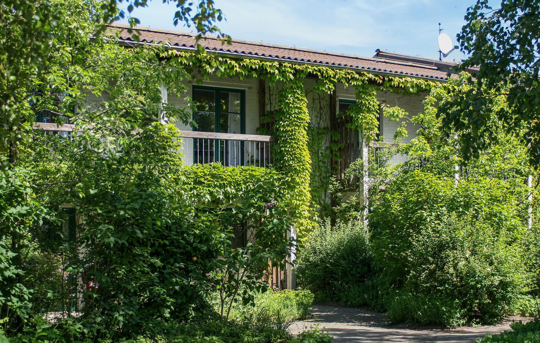 Un edificio con tetto in tegole, immerso nel verde e con un viale che conduce all'ingresso.