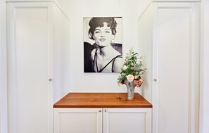 A hallway with a white door, a black and white portrait on the wall, and a wooden table with a vase of flowers. - 41 - Ferienwohn Sissi & Franzl (Kuhlen-Wendorf)