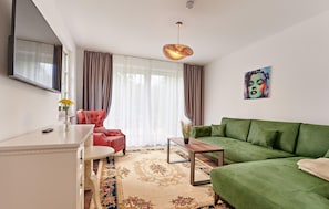 Uma sala de estar moderna com um sofá verde, uma poltrona vermelha, uma mesa branca e um tapete decorativo.