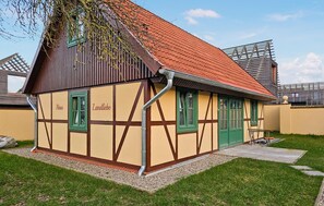 A traditional half-timbered house with a sloped red roof, a green door, and a small garden area. - 45 - Ferienhaus Landlust (Kuhlen-Wendorf)