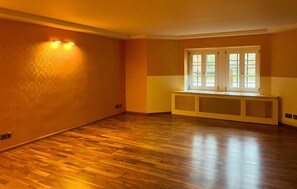 Quarto com piso de madeira, janela com vários painéis e um banco embutido.