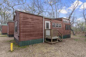 Eine Holzhütte mit einer Veranda und einer kleinen Treppe, die zu einer Tür führt.