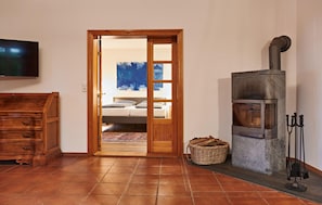 A room with a wooden dresser, a fireplace, a television, and a door leading to a bedroom. - 48 - Ferienhaus XL Oliver (Kuhlen-Wendorf)