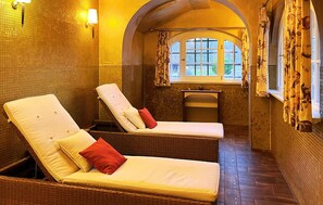 Ett spa-rum med två justerbara fåtöljer, ett litet handfat och ett fönster med gardiner.