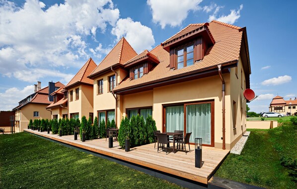 Una hilera de casas modernas con techos de tejas rojas, ventanas grandes y un césped cuidado.