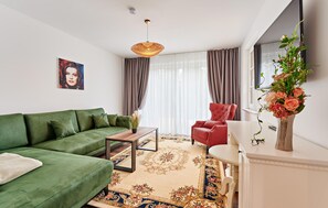 A modern living room with a green sofa, a red armchair, a coffee table, and a decorative vase. - 42 - Ferienwohn Sissi & Franzl (Kuhlen-Wendorf)