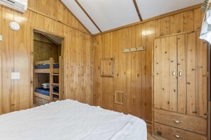 Ein Zimmer mit Holzboden, Stockbetten, einem Kleiderschrank und einem Bett.