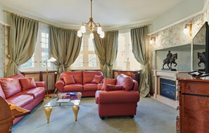 A living room with a glass coffee table, leather sofas, a fireplace, and a chandelier. - Stunning apartment in Kuhlen-Wendorf with sauna (Kuhlen-Wendorf)