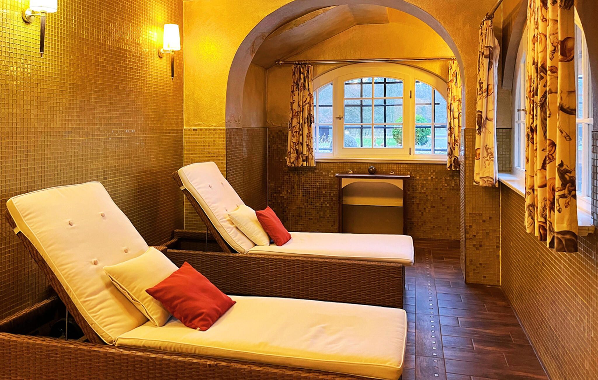 Un cuarto de spa con dos sillones reclinables, un lavamanos pequeño y una ventana con cortinas.