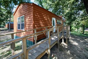 A wooden cabin with a deck, surrounded by trees. - Two Room Trout Pond Cabin - Sleeps 6 to 8 guests, ADA Accessible (Gore)