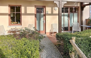 Ein Gebäude mit befestigtem Eingangsbereich, einem Außenbereich mit Sitzgelegenheiten und einem Holzzaun.