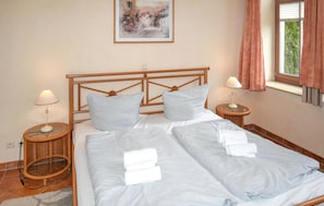 A double bed with two pillows, a nightstand with a lamp, a painting on the wall, and a window with curtains. - Pet friendly apartment in Kühlungsborn with WiFi (Kühlungsborn)