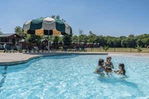 A swimming pool with a large umbrella, lounge chairs, and a fence in the background. - Bungalow Cabin Studio - Sleeps 4 to 6 guests. (Gore)