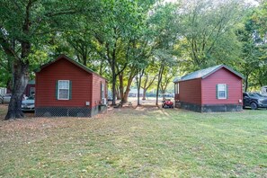 Two red cabins with a picnic table and a red vehicle in the background. - Cabana - Sleeps up to 6 guests. (Gore)
