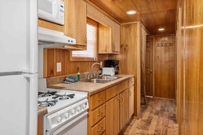 A compact kitchen with a gas stove, a microwave, and a coffee maker. - Double Deluxe Cabin - Sleeps 8 to 10 guests. (Gore)
