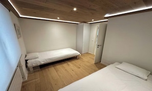 A room with two beds, wooden flooring, and recessed ceiling lighting. - COMBINING CONTEMPORARY DESIGN WITH BREATHTAKING VIEWS OF THE ICONIC MATTERHORN (Zermatt)