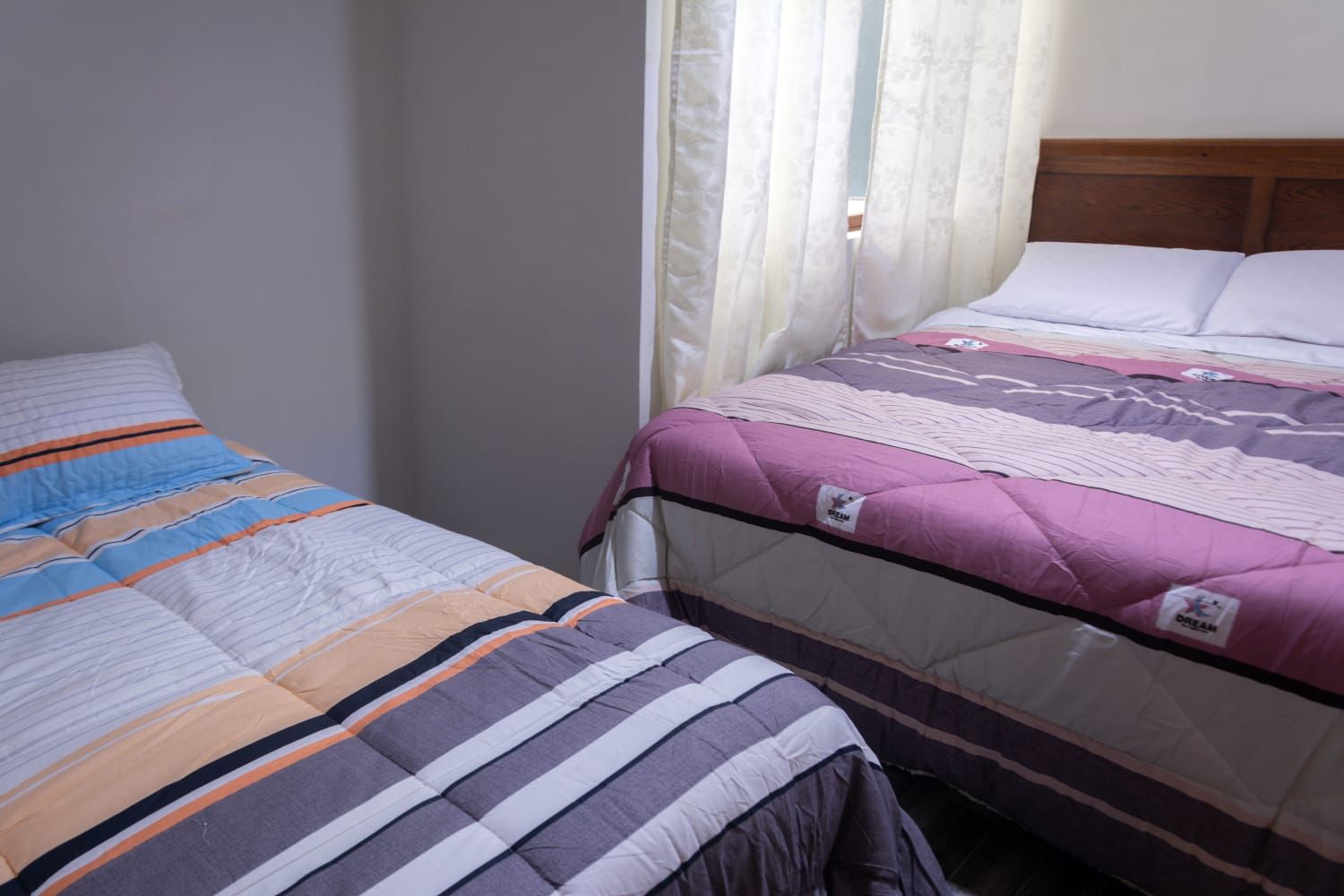 Un dormitorio con dos camas, una con cubrecama a rayas y la otra con manta acolchada.