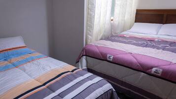 Un dormitorio con dos camas, una con cubrecama a rayas y la otra con manta acolchada.