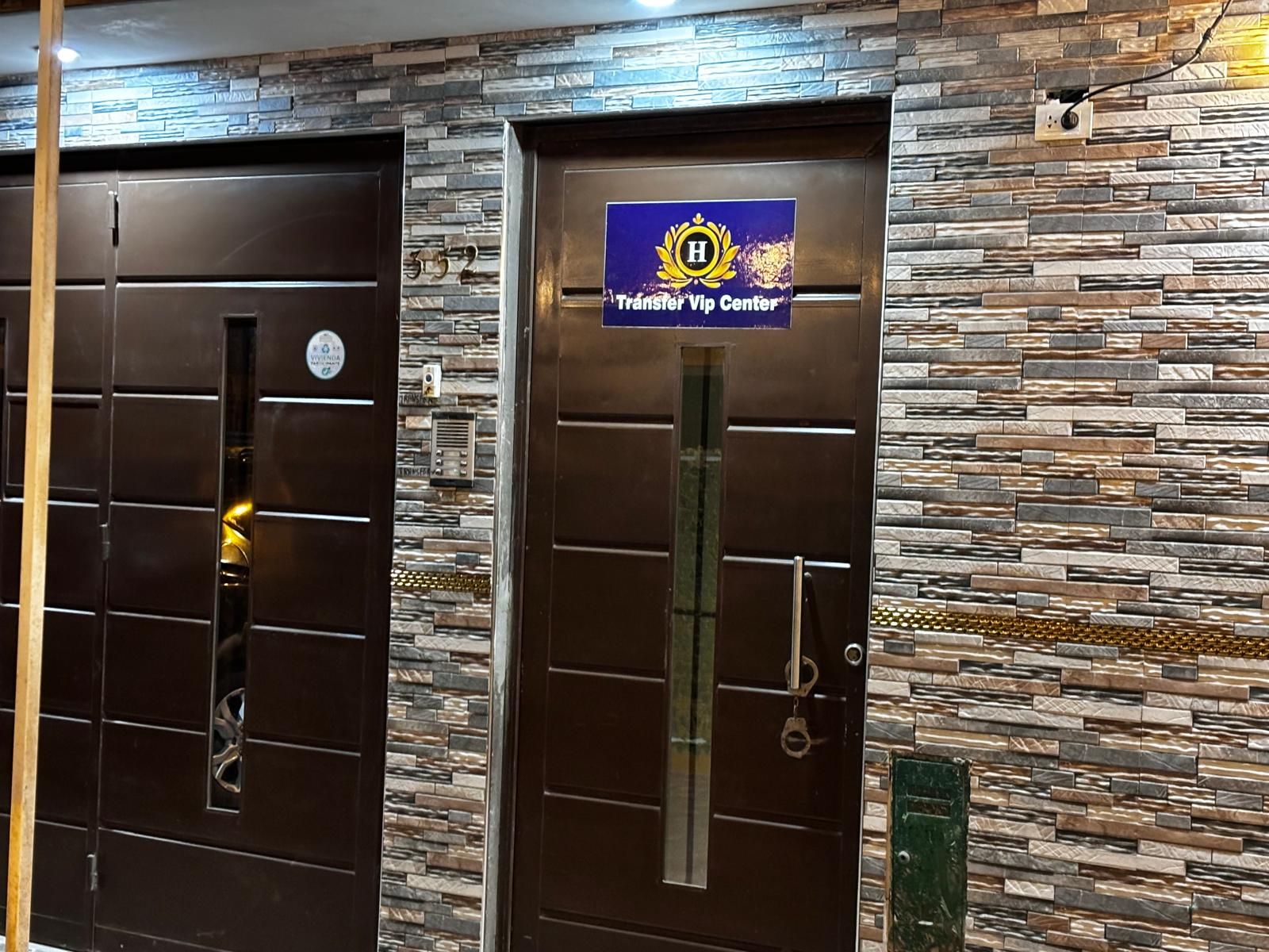 Dos puertas con un muro de piedra de fondo y un cartel que indica un centro de traslados VIP.