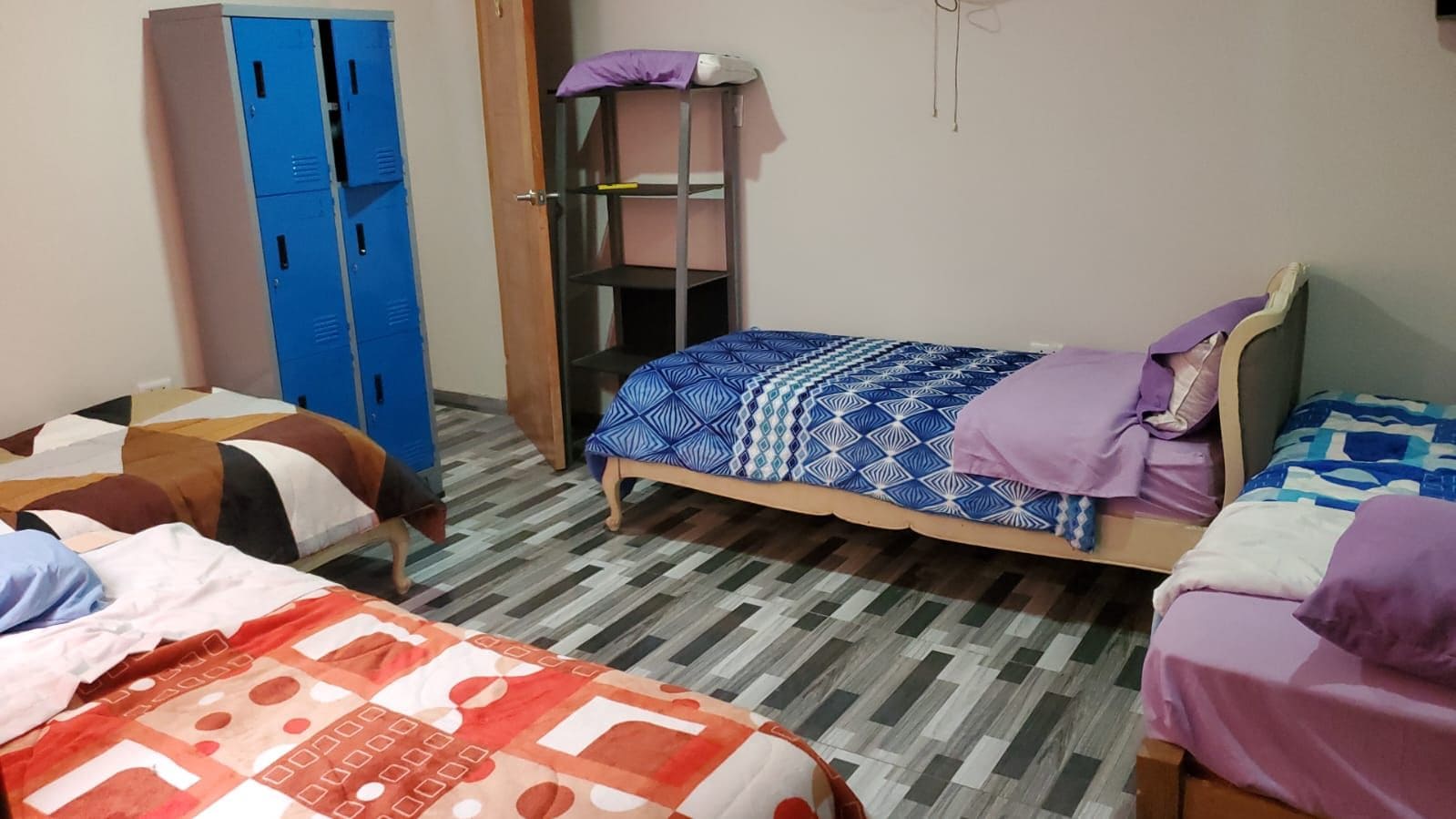 Quarto tipo dormitório com duas camas, um guarda-roupa e uma estante.