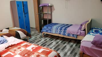 Quarto tipo dormitório com duas camas, um guarda-roupa e uma estante.
