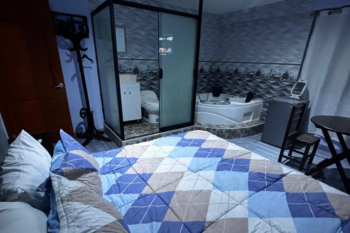 Camera d'albergo con un letto, una scrivania, una sedia, una vasca da bagno e una porta vetrata che conduce al bagno.